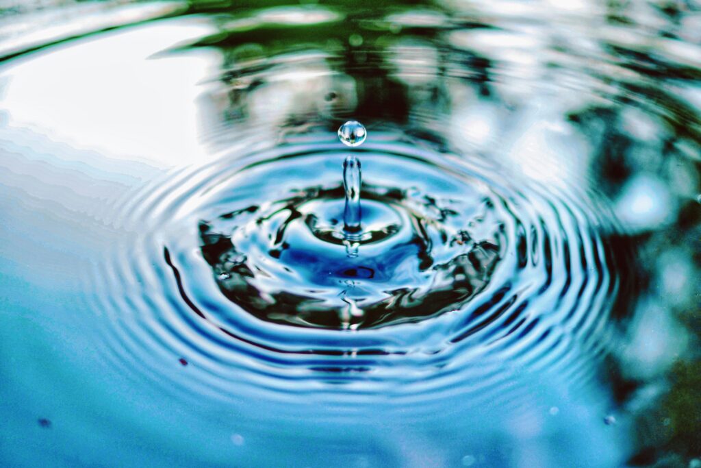 A water droplet creates ripples in a calm blue surface, showcasing the beauty of motion and stillness in nature.
